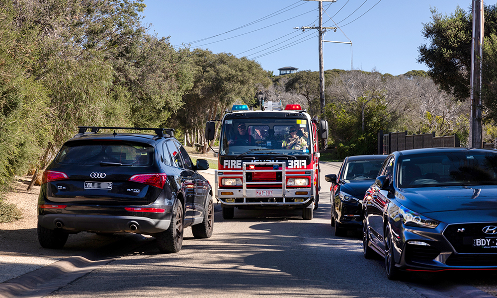A fire truck is unable to pass through a narrow suburban street because cars are parked on both sides of the street.