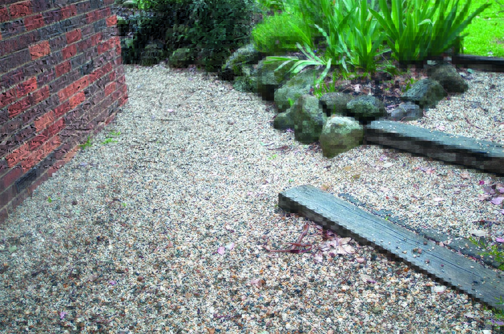 A pebble path next to a brick home.