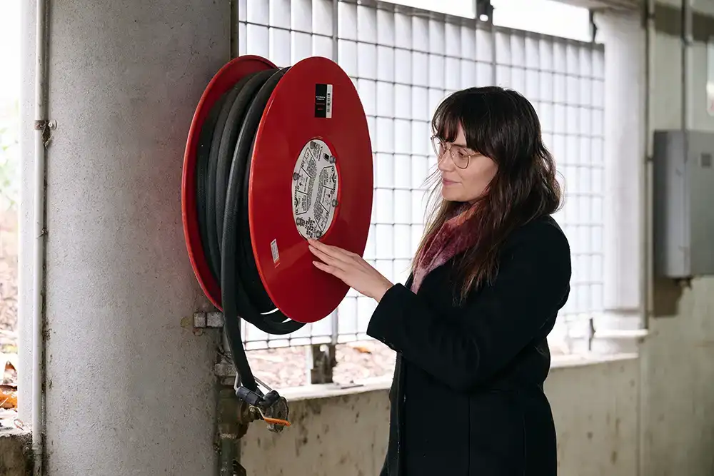 A person is pointing at fire hose reel instructions on a red reel.