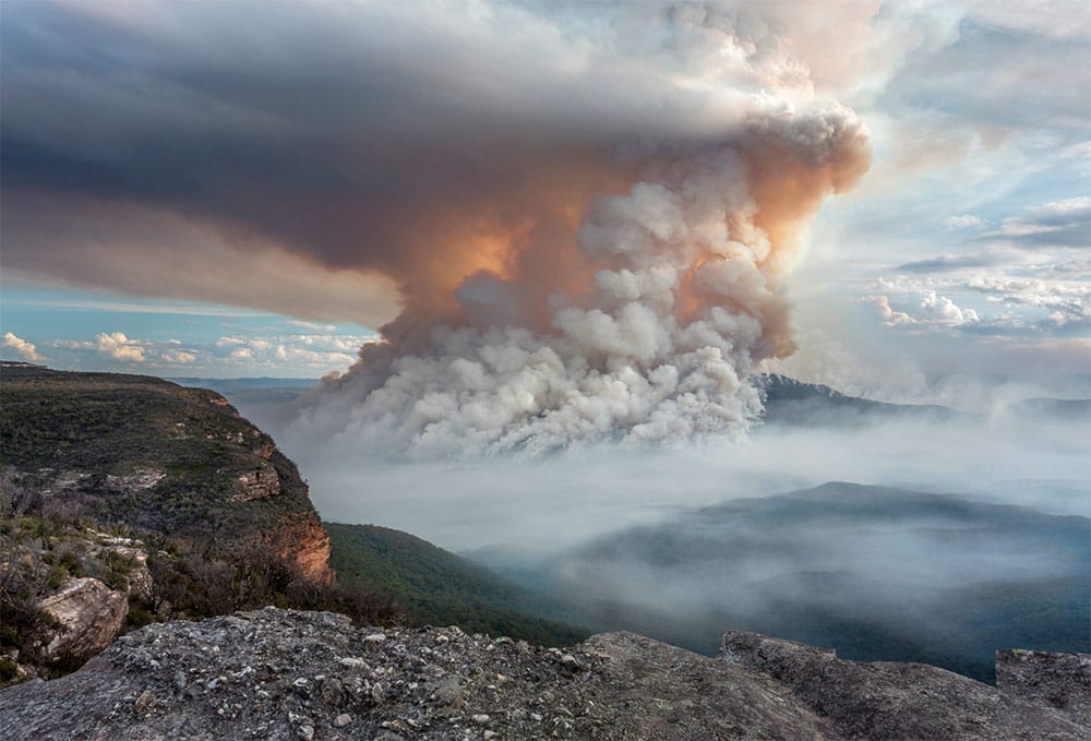 Smoke rising high into the atmosphere above a Victorian mountain landscape.