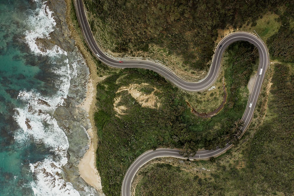 A birds eye view of a windy, isolated, single lane coastal road.