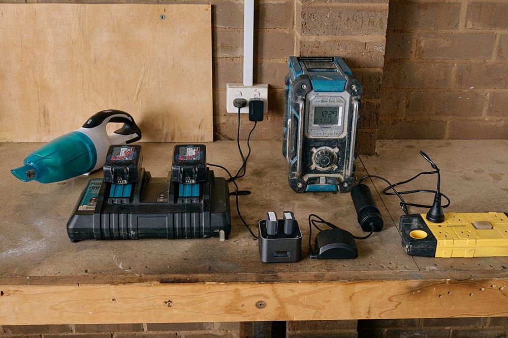 Power tool and other types of batteries on charge on a garage bench.