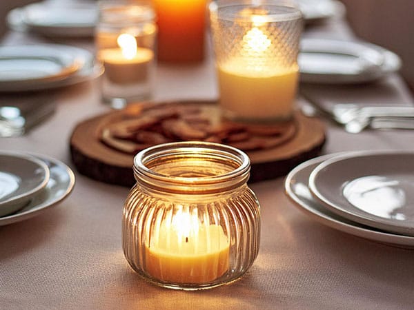 A glass jar is on a dining table that is set for a dinner party.