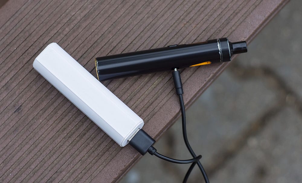 Two vapes charging on a hard surface.