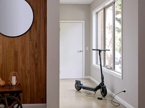 A black electric scooter charging in a hallway.