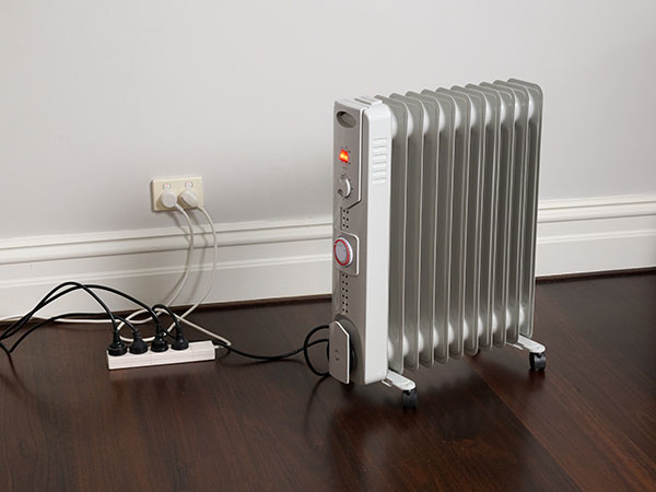 Electric heater plugged into a power board with all point used, that is then plugged into the wall power point. 