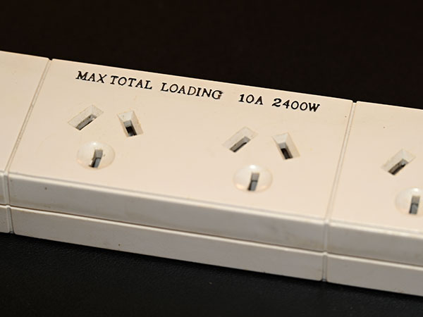 Close up of a 2,400 watts rating on a power board with three plug sockets.