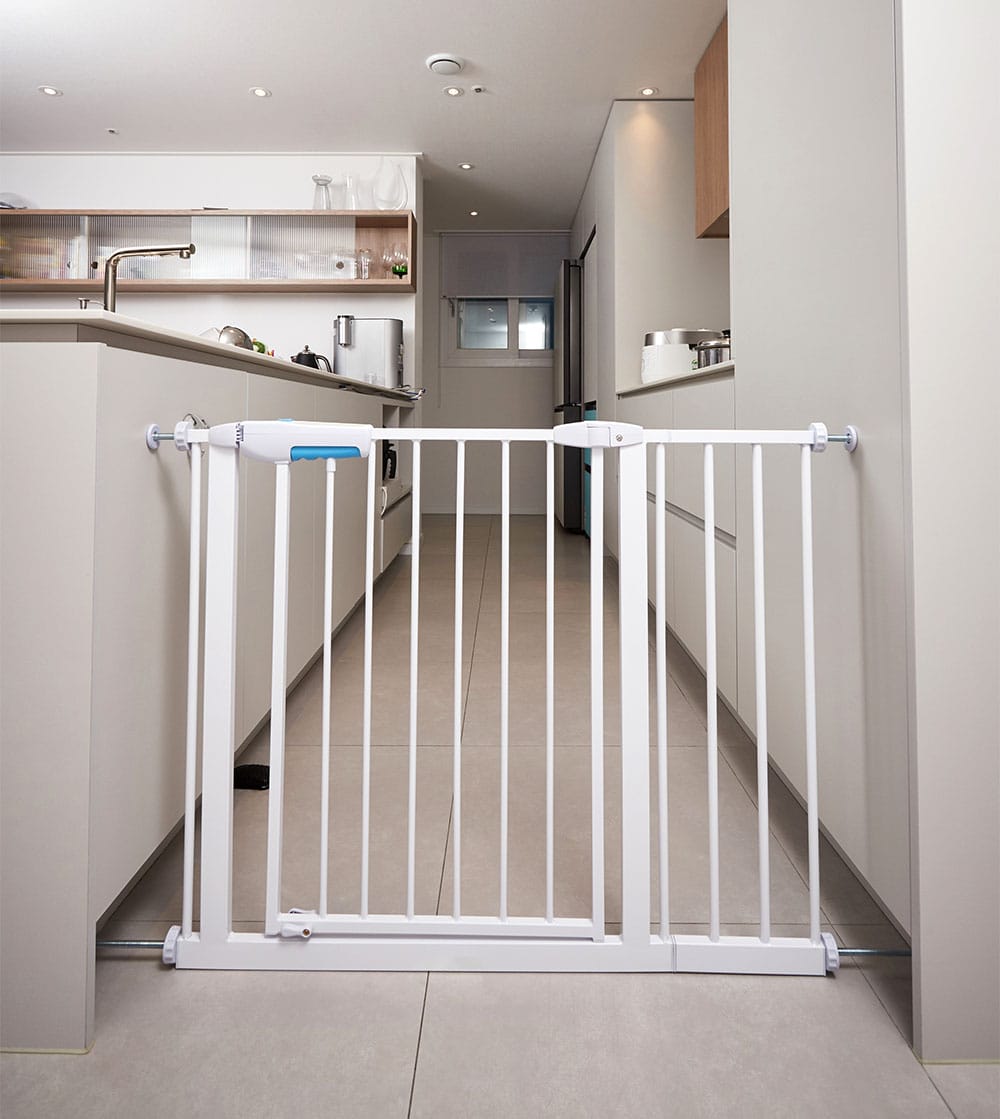 White baby gate installed between two sides of a galley kitchen blocking access to a kitchen