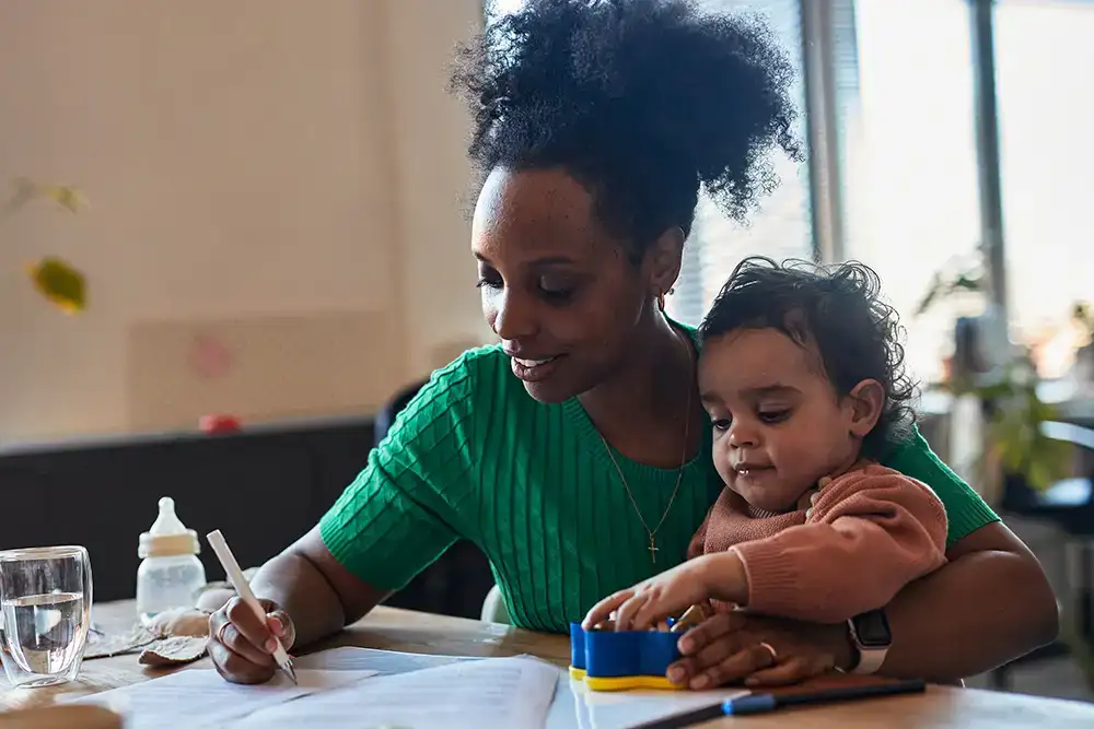 A woman writing out a fire plan with a young toddler on her lap.