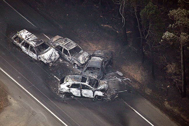 Four burnt out, crashed cars on a road.
