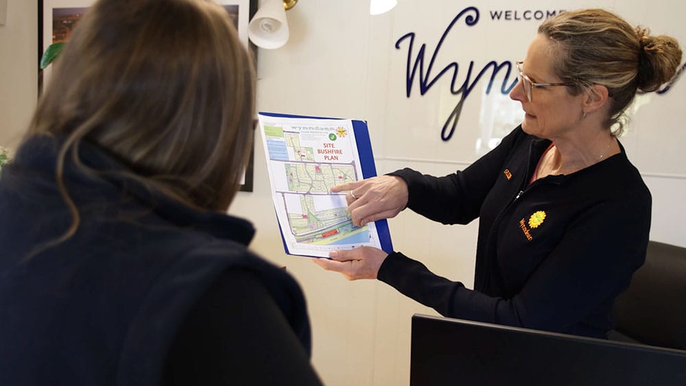 A business owner showing a client through their business' bushfire plan, indicating features on a site map.