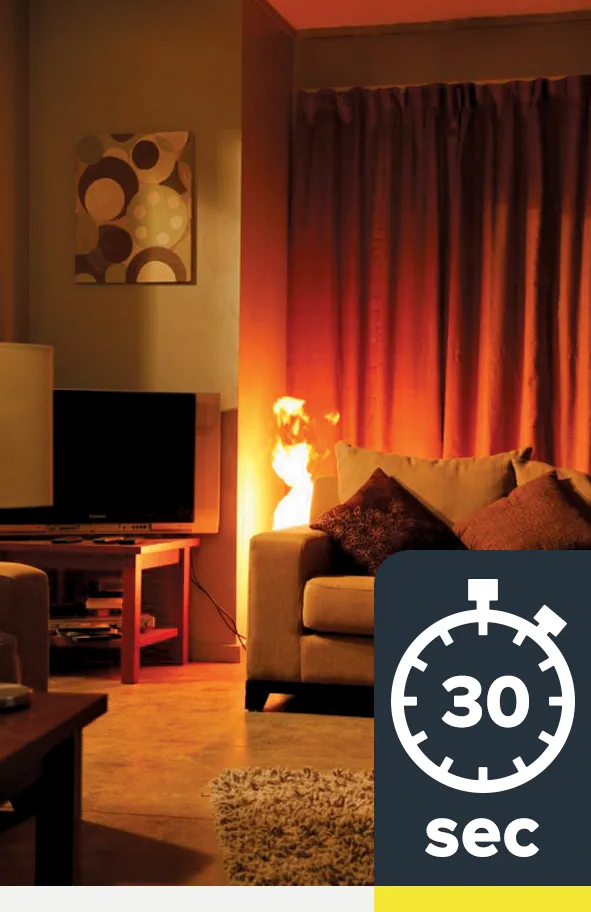 A fire has started behind a couch in a lounge room and the flames are about 60cm high.